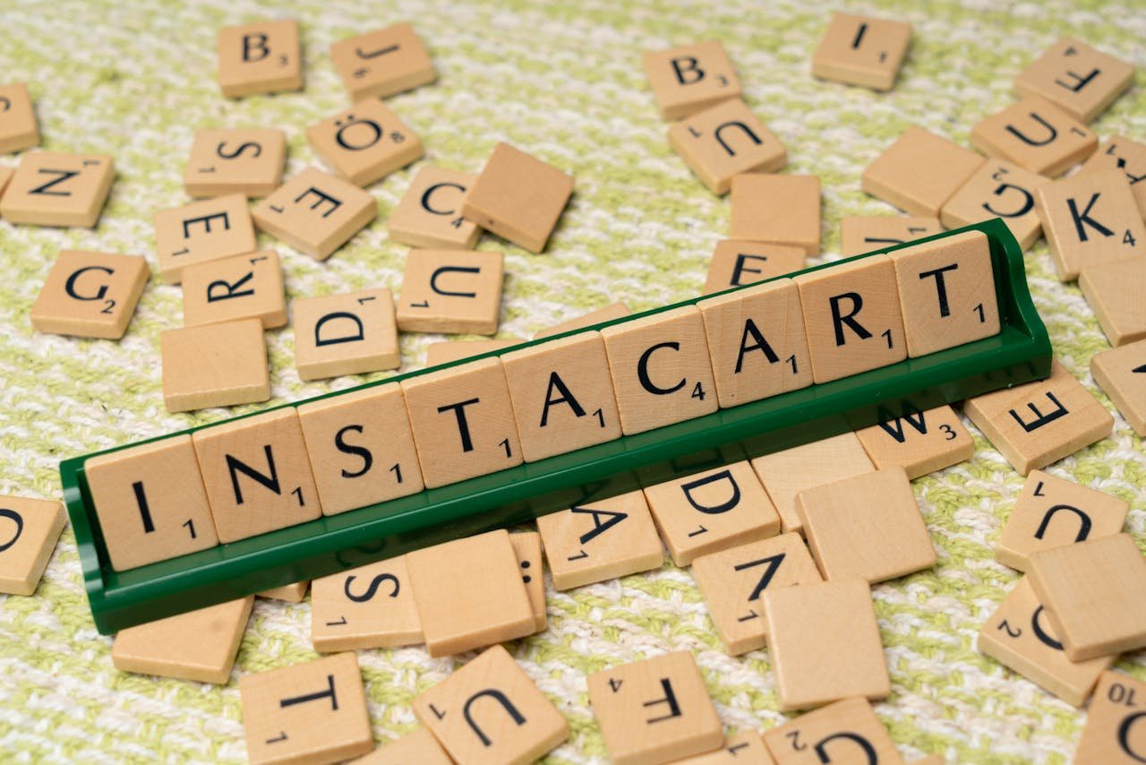 services-bg Wooden Scrabble tiles spelling 'INSTACART' on a green holder with scattered tiles.